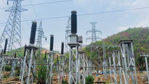 145 kV SF6 circuit breaker with transmission towers and green hills in the background